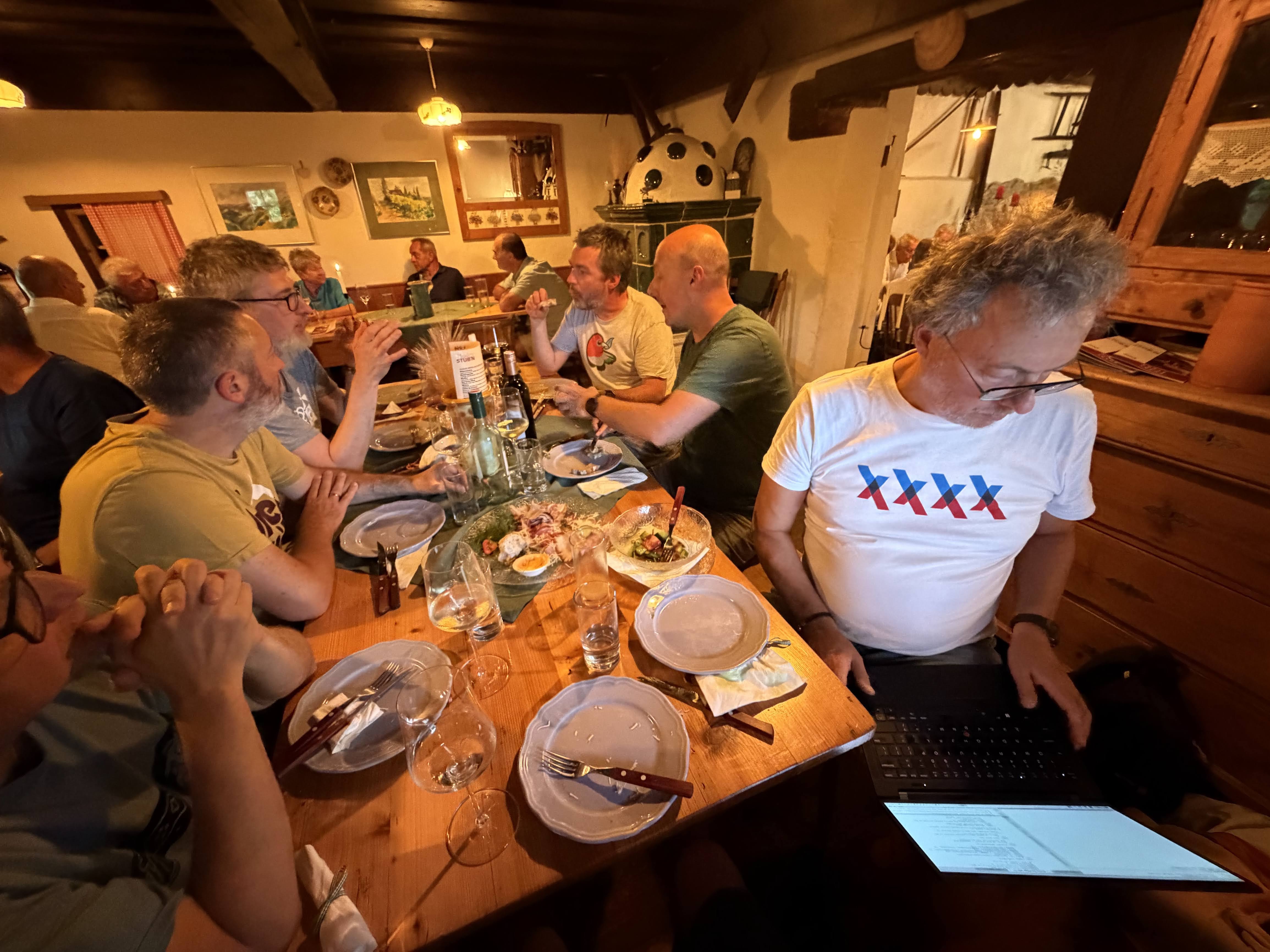 Hack and dine. People having diner at a Buscheschank, one is still hacking.